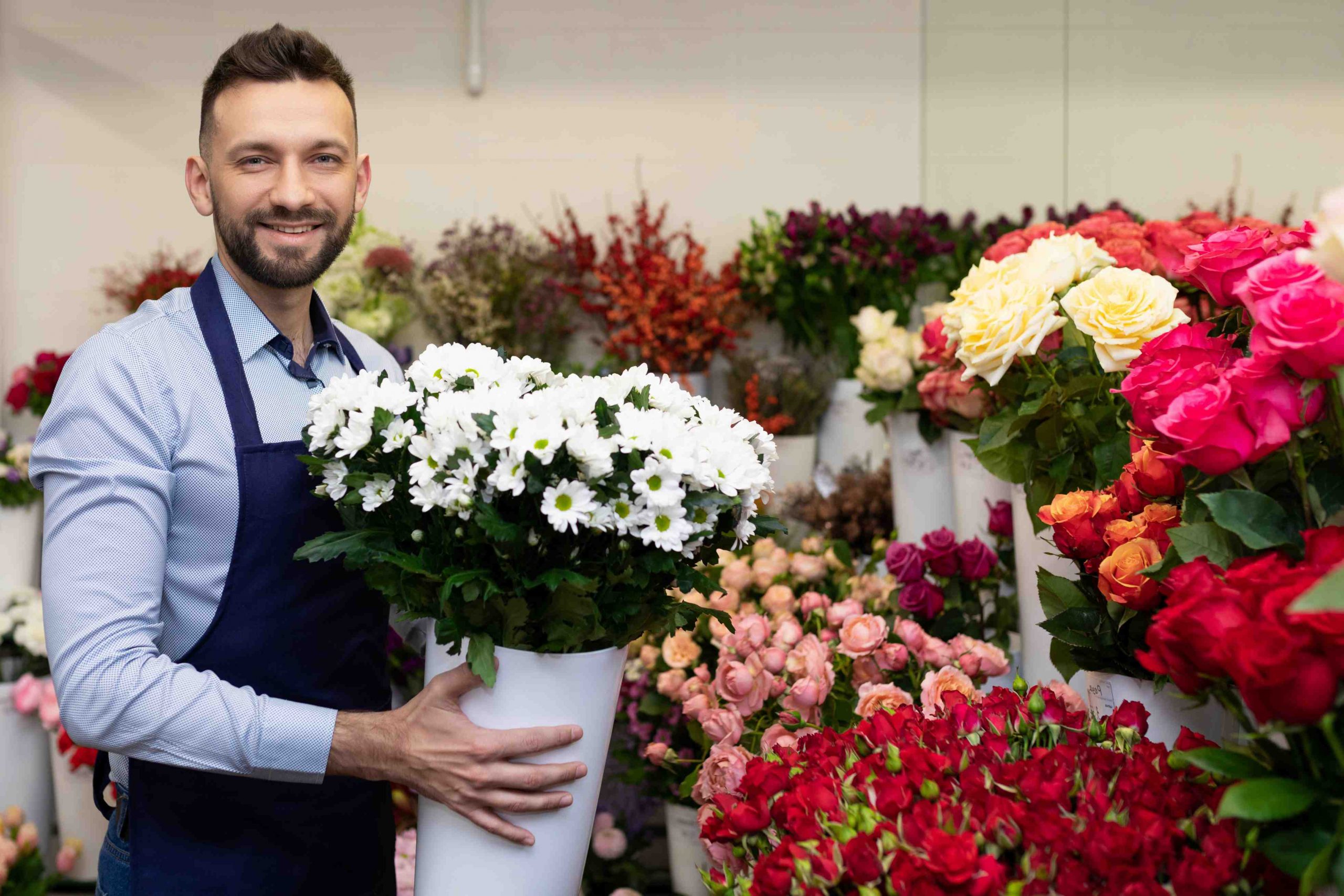 man standing next to flower bouquets with bouquet of flower in his hands