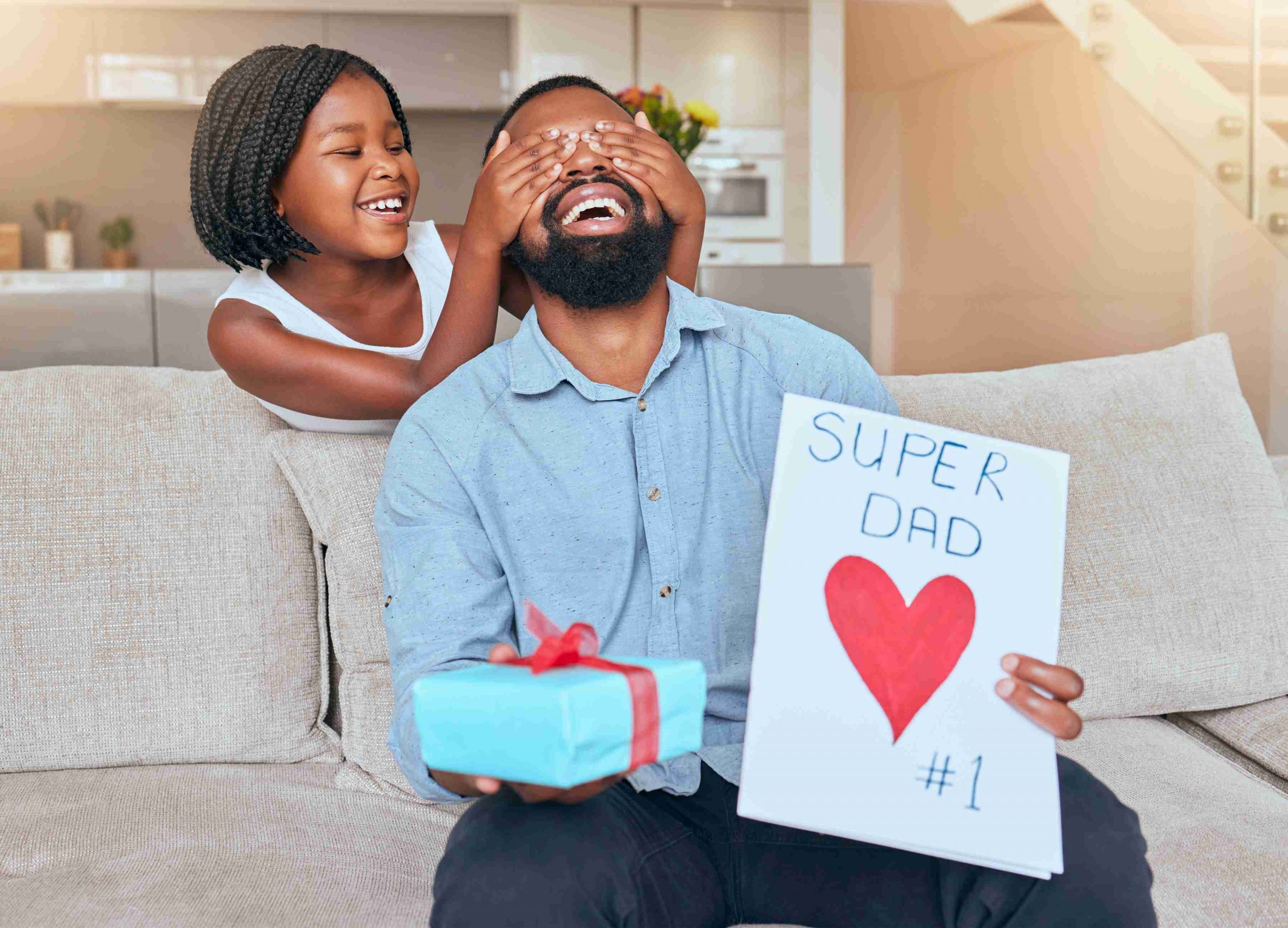 smiling child covering her dad's eyes and surprises him