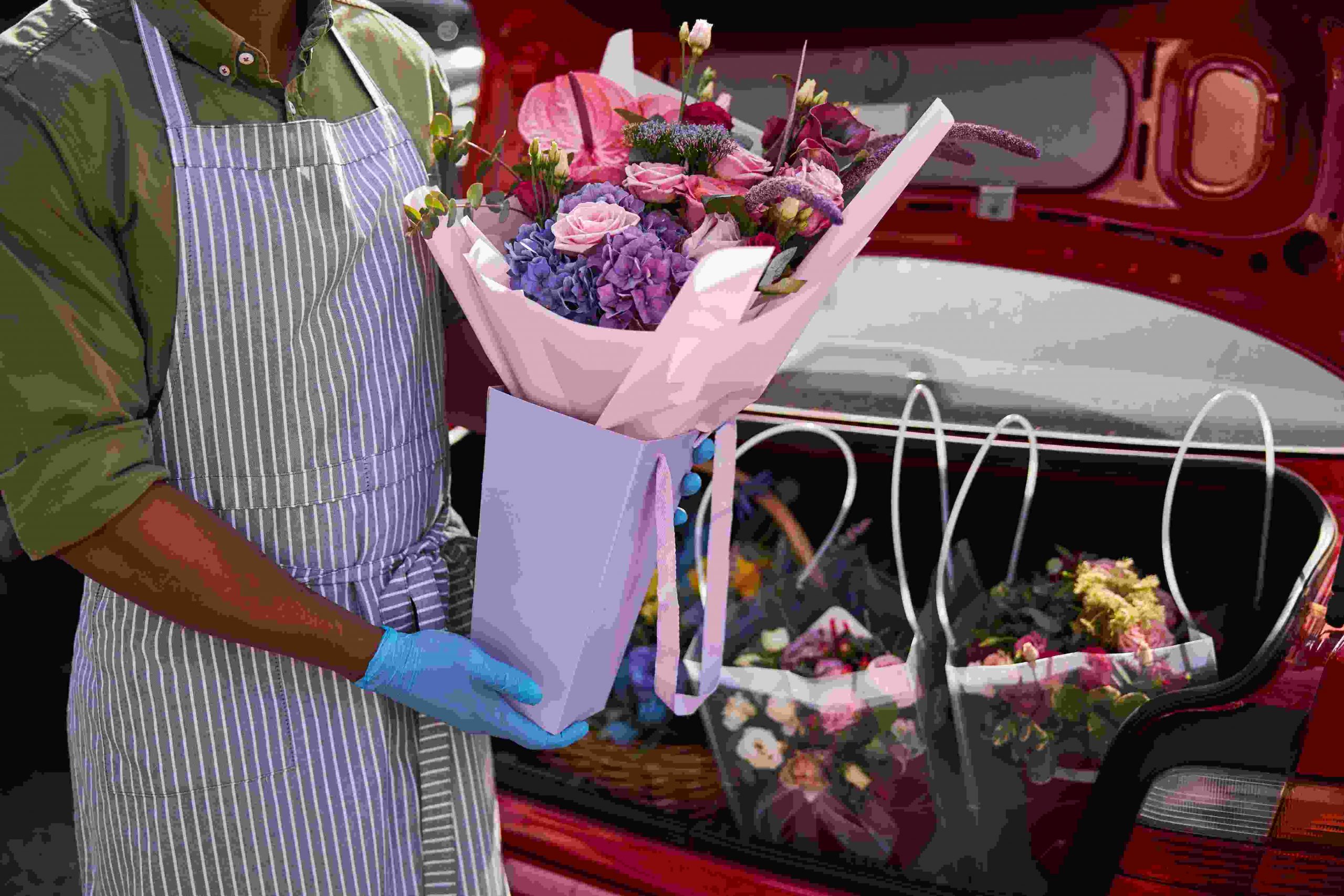 Florist store worker packing flowers to a trunk