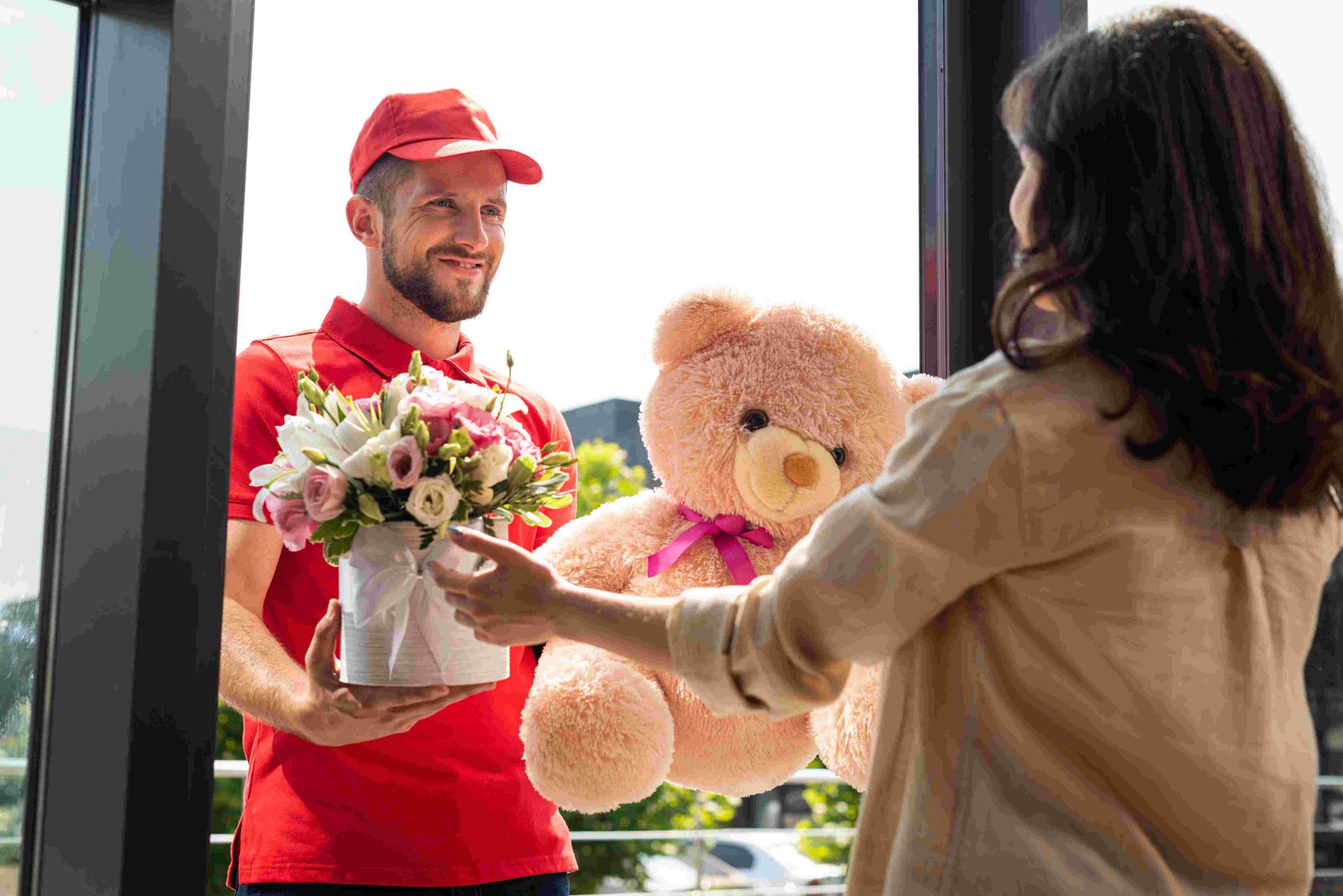 delivery man holding bouquet of flowers and teddy bear