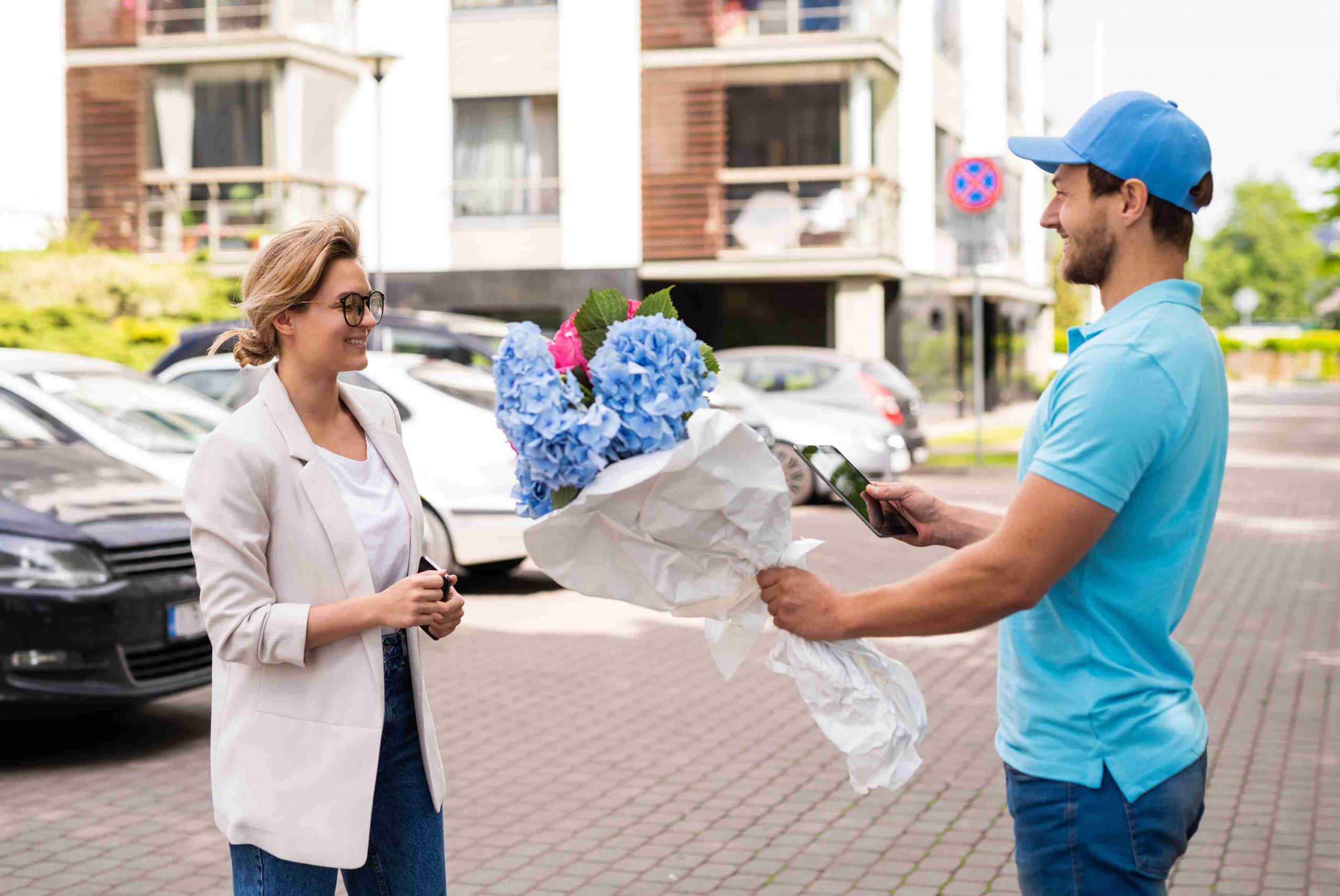 delivery man in blue uniform delivers flowers to a woman