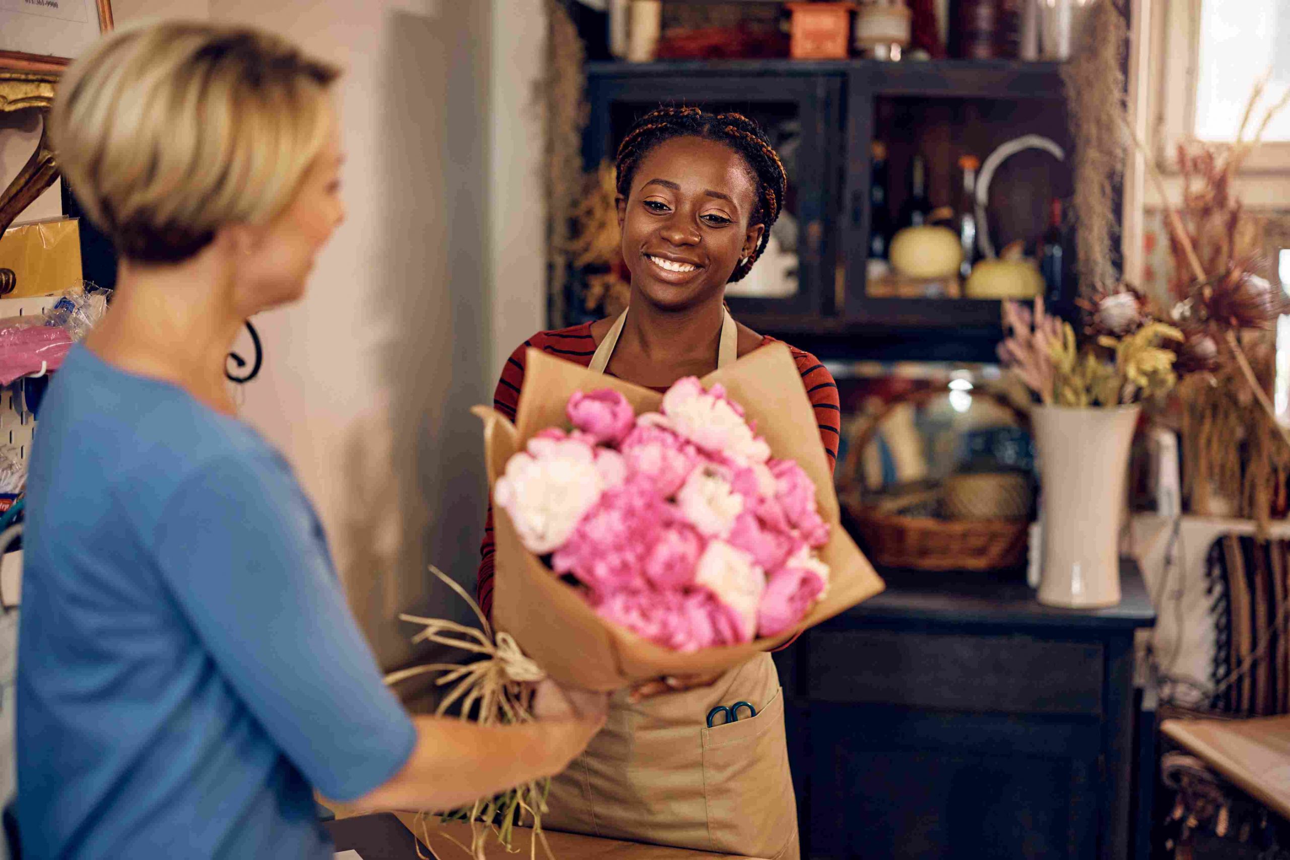 african-american woman giving flowers to blond woman