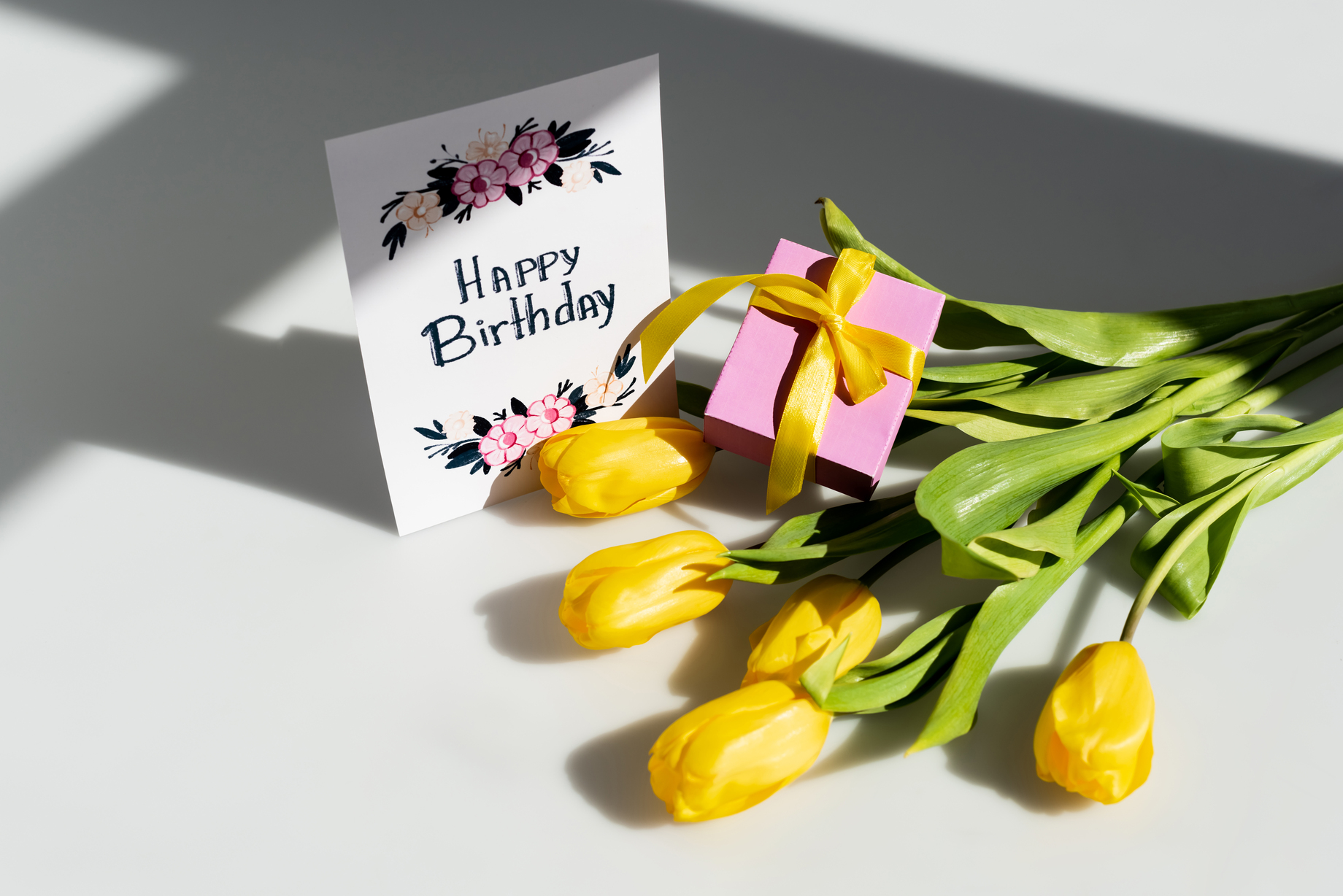 Birthday flowers beside a greeting card and present